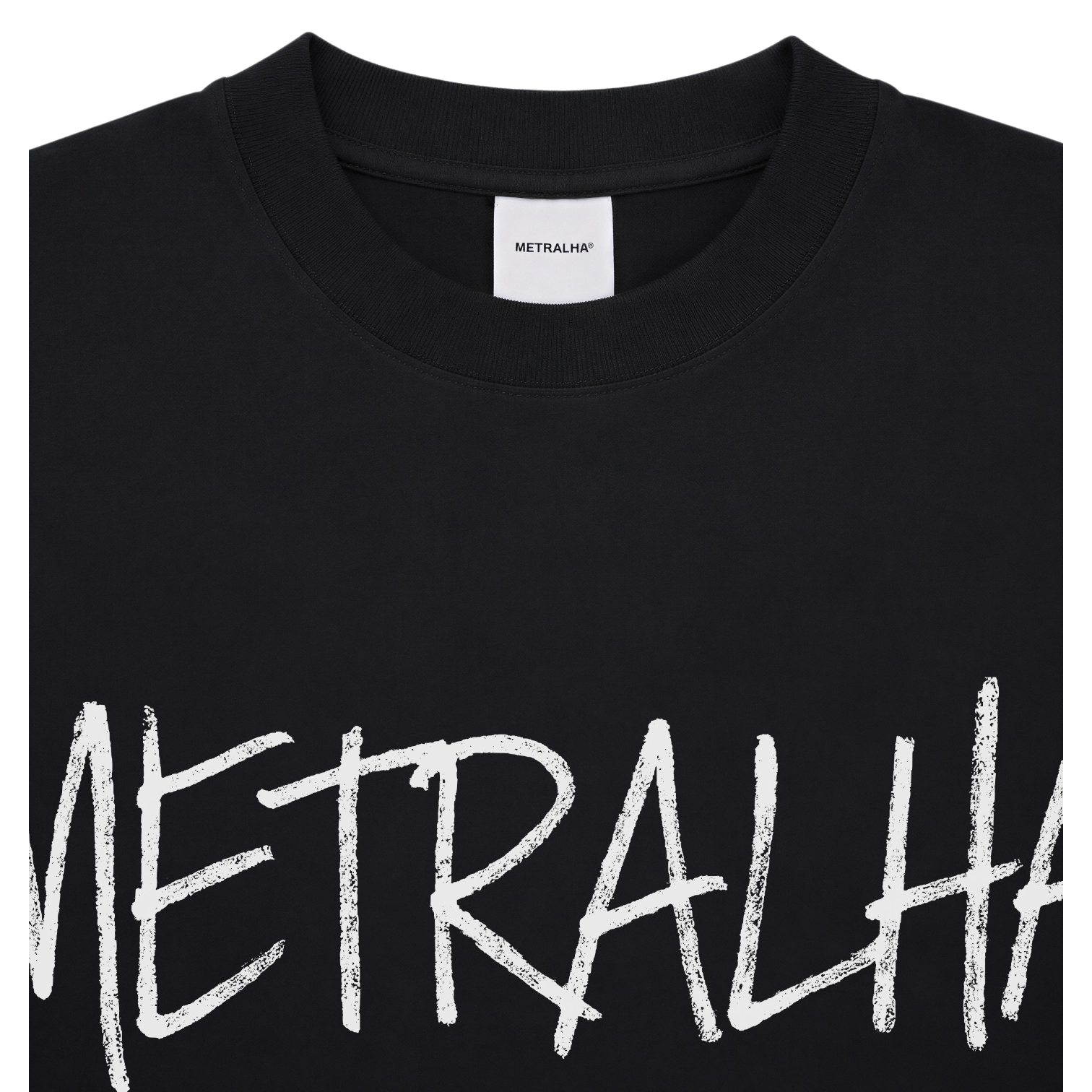 Close-up of a black crewneck sweatshirt featuring a large white textured brushstroke graphic spelling 'METRALHA' across the chest, with a white neck label showing the brand 'METRALHA'.