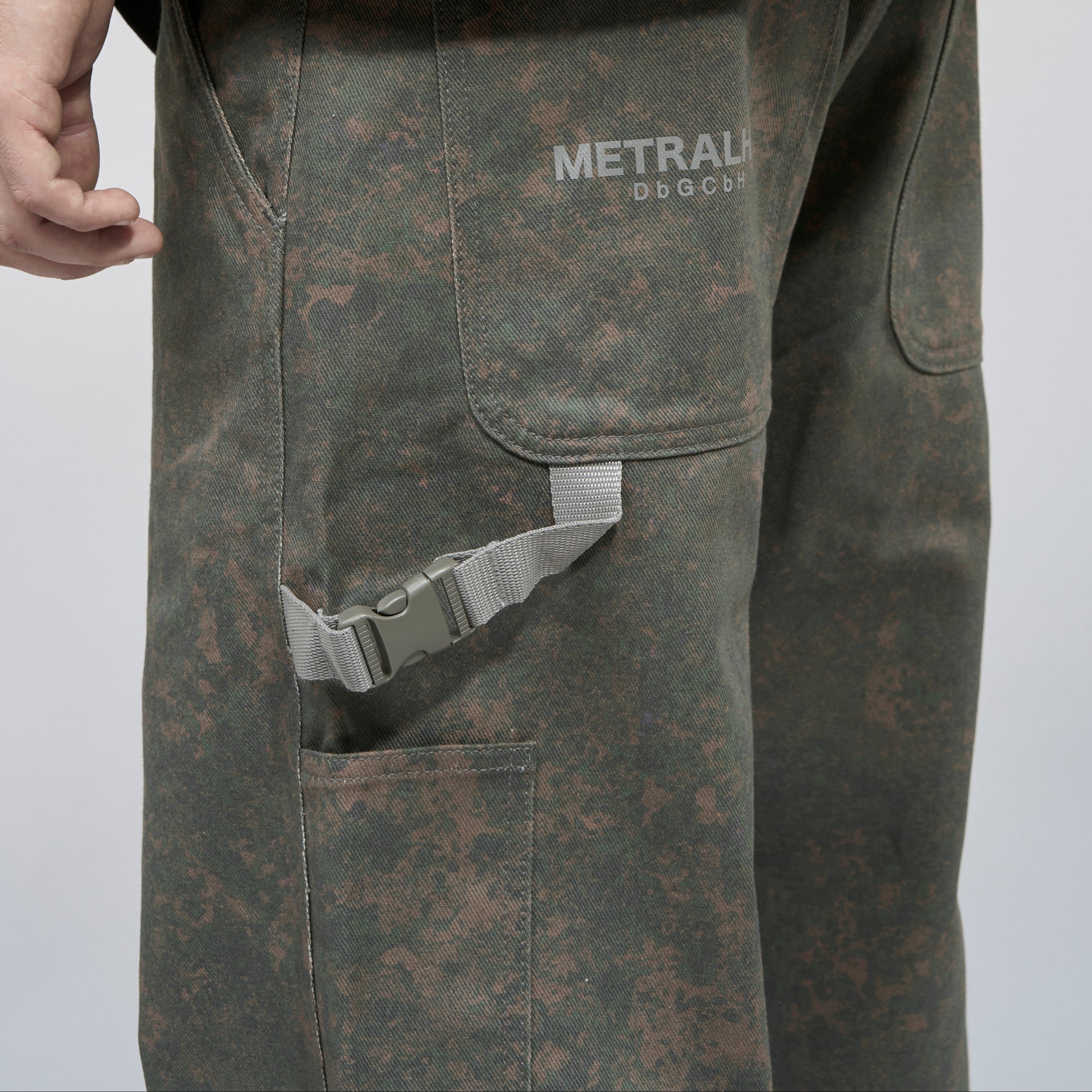 Dark camouflage pants with 'METRALHA' branding on a light gray background